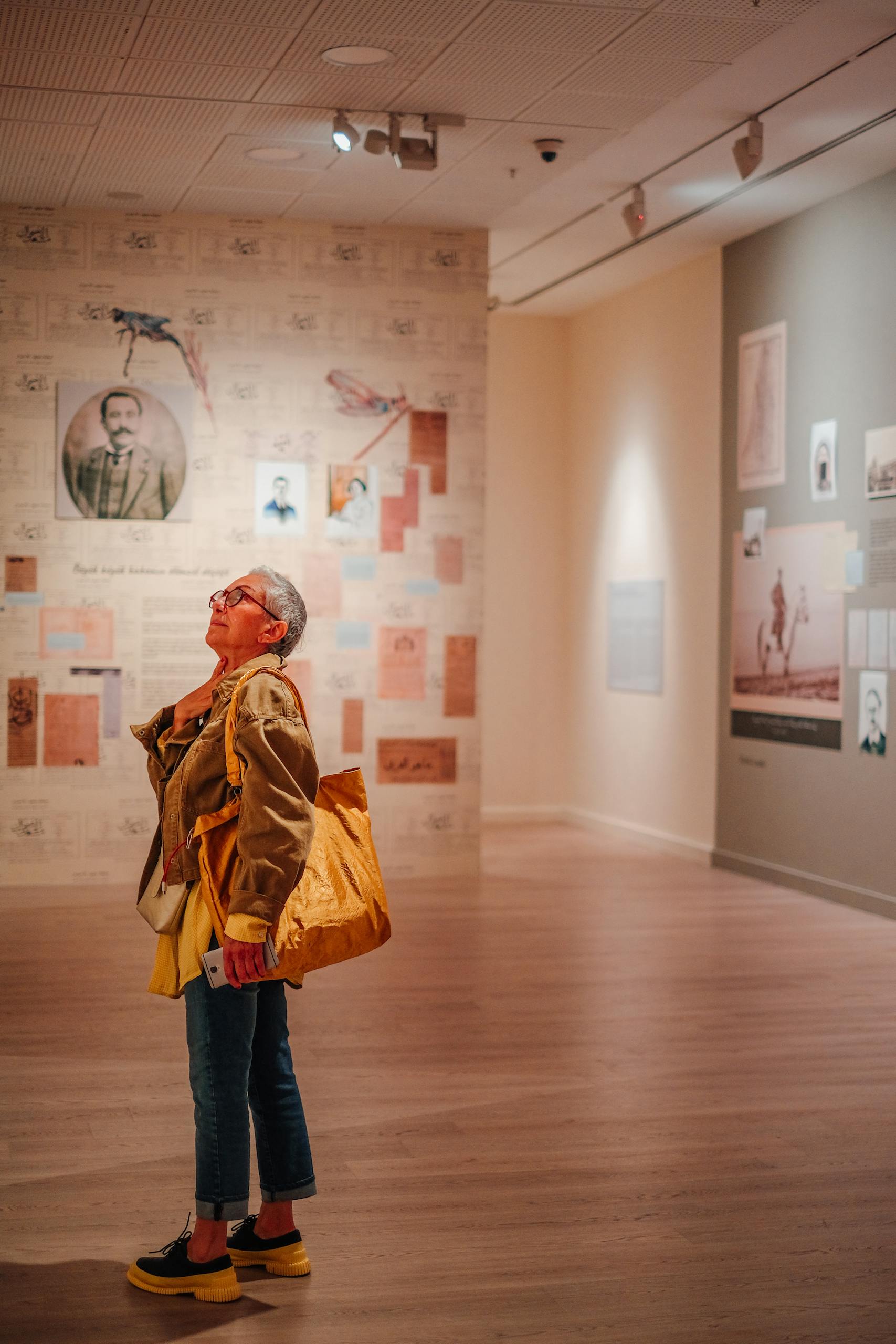 Elderly woman exploring an art exhibition in a contemporary museum space.